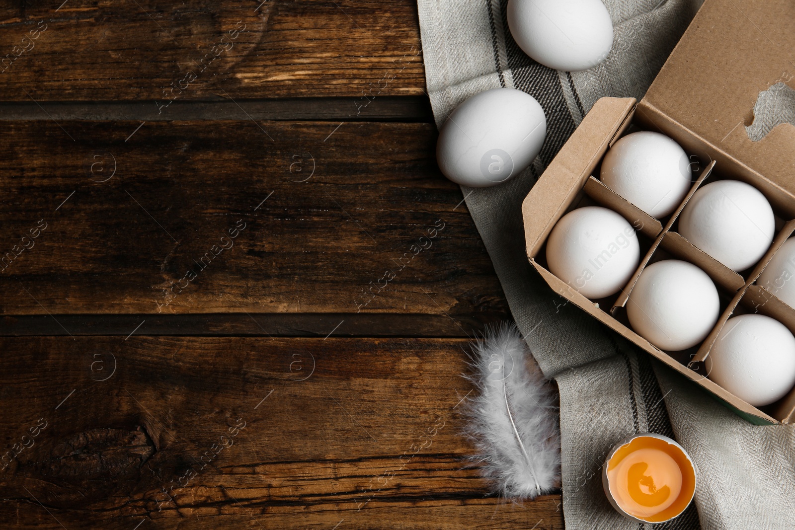 Photo of Fresh raw chicken eggs in box on wooden table, flat lay. Space for text