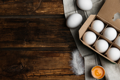 Photo of Fresh raw chicken eggs in box on wooden table, flat lay. Space for text