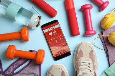 Photo of Flat lay composition with fitness equipment and smartphone on light blue background