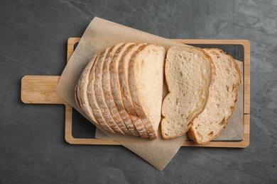 Photo of Board with cut bread on grey table, top view