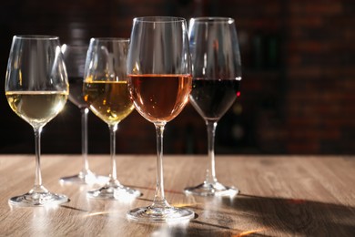 Different tasty wines in glasses on wooden table, space for text
