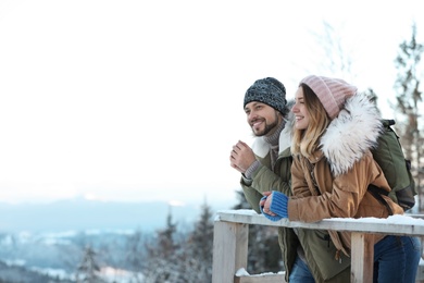 Photo of Couple with backpacks enjoying mountain view during winter vacation. Space for text