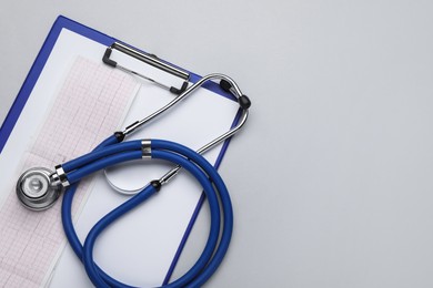 Photo of Stethoscope, clipboard and cardiogram paper on white background, top view. Space for text