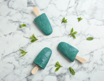 Flat lay composition with delicious spirulina popsicles on marble table