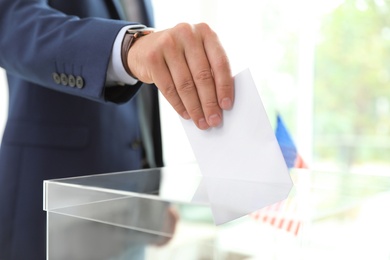 Man putting ballot paper into box at polling station, closeup