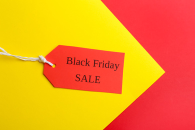 Red tag with words BLACK FRIDAY SALE on color background, top view