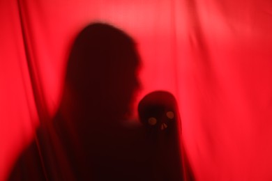 Photo of Silhouette of creepy ghost with skull behind red cloth, space for text