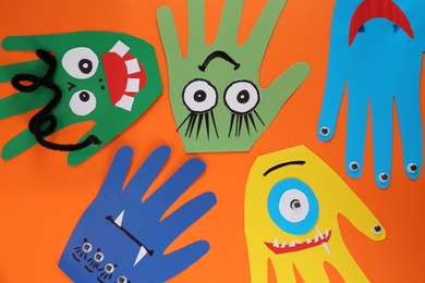 Funny hand shaped monsters on orange background, flat lay. Halloween decoration