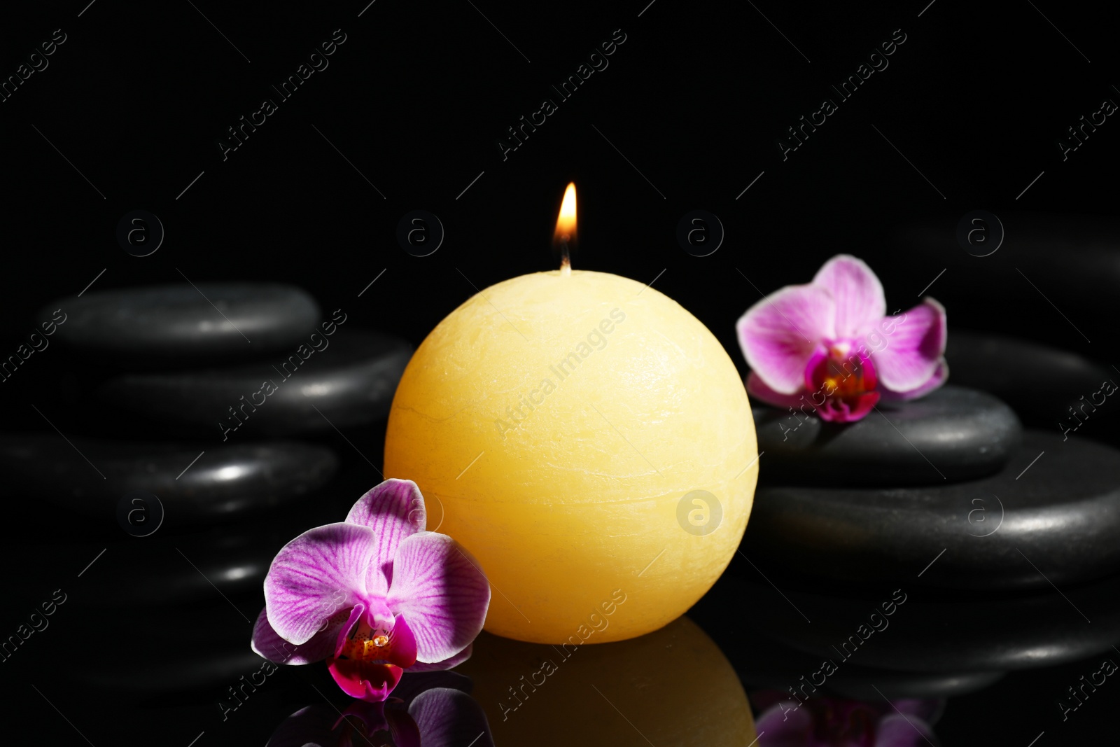 Photo of Composition with candle and spa stones on black background