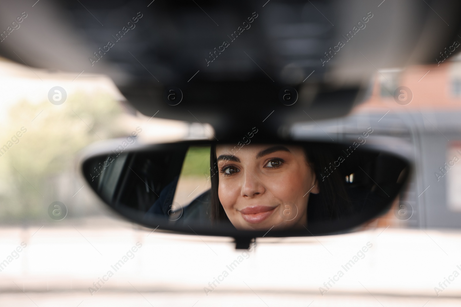 Photo of Woman adjusting rear view mirror inside her car, closeup