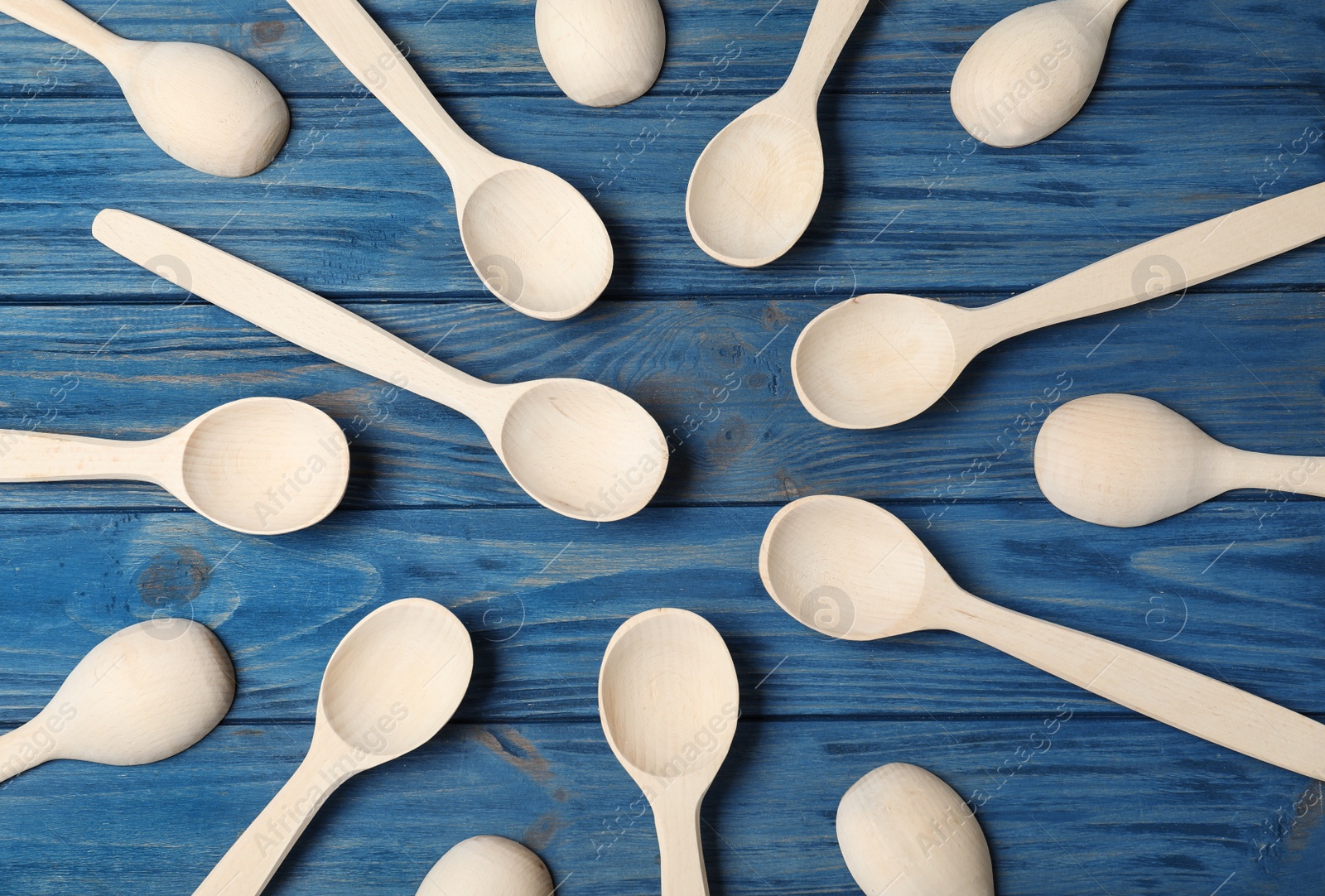 Photo of New wooden spoons on blue table, flat lay