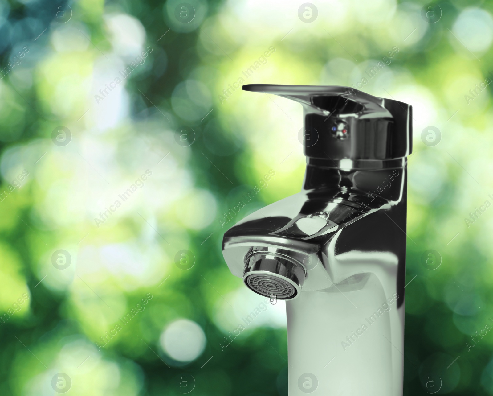 Image of Water drop flowing from tap outdoors on sunny day, bokeh effect