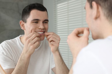 Photo of Young man applying whitening strip on his teeth indoors