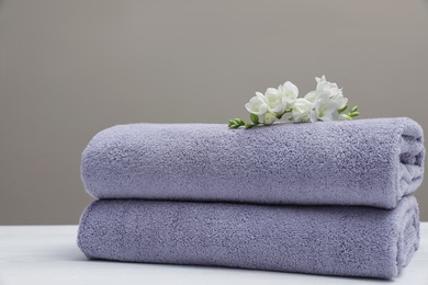 Photo of Stack of fresh towels with flowers on table. Space for text