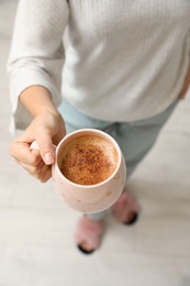 Photo of Woman holding cup of coffee indoors, above view
