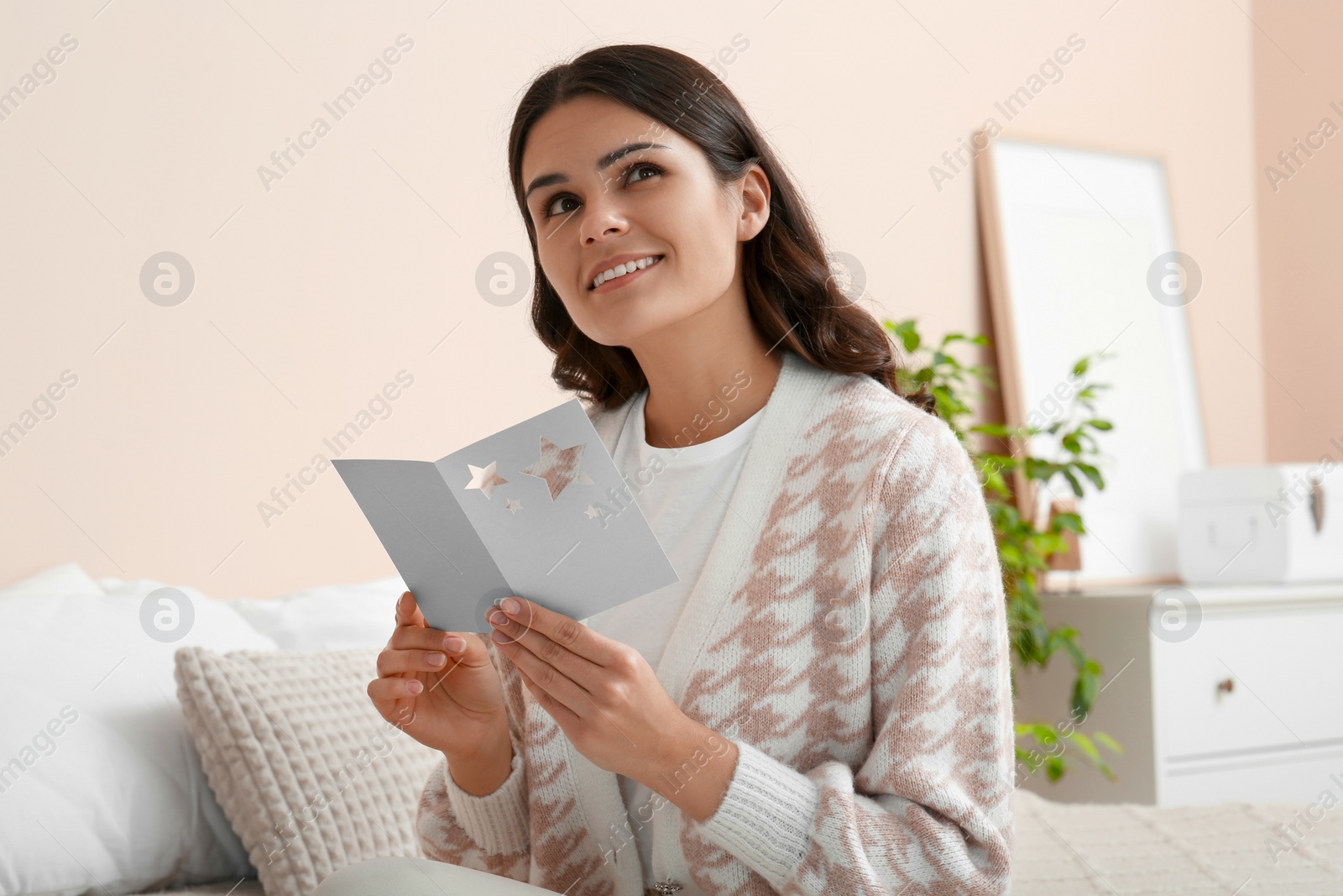 Photo of Young woman with greeting card in bedroom