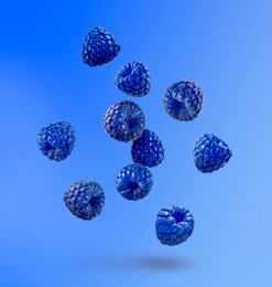 Image of Many fresh blue raspberries falling on blue background