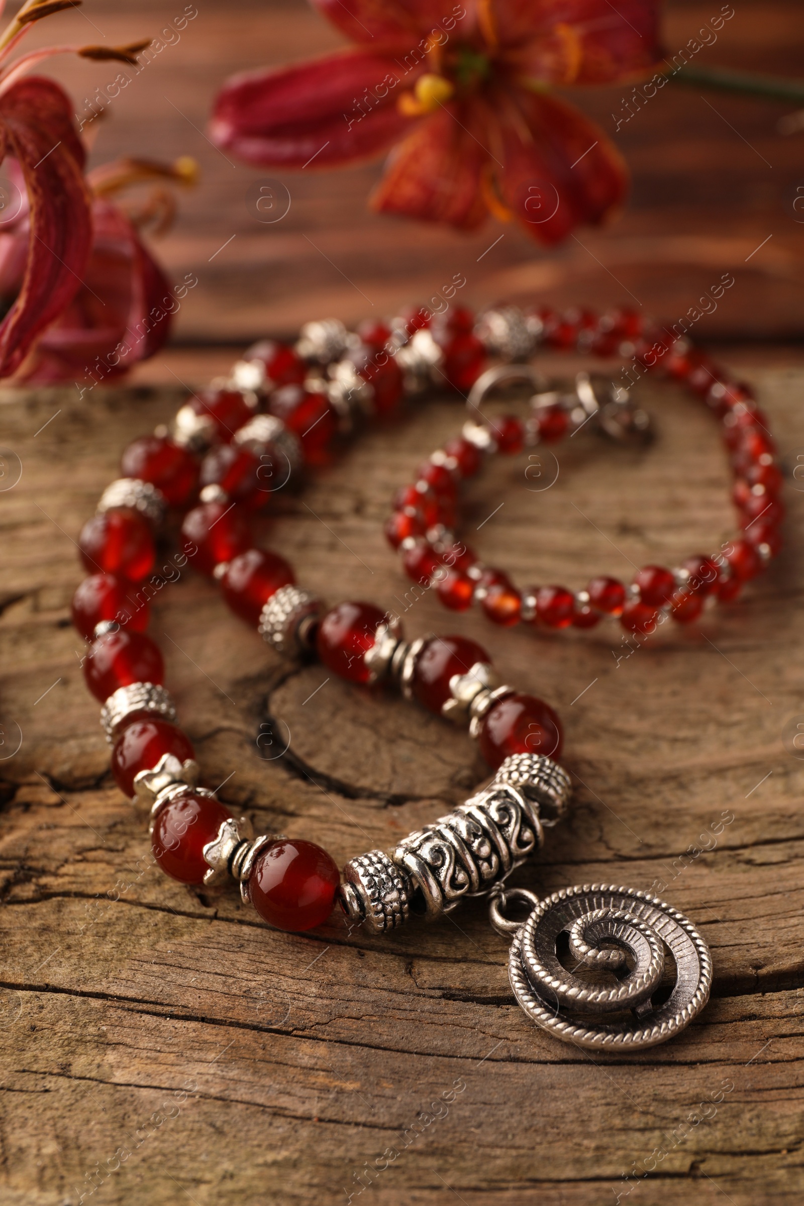 Photo of Beautiful necklace with gemstones on wooden surface, closeup