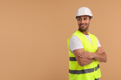 Engineer in hard hat on beige background, space for text