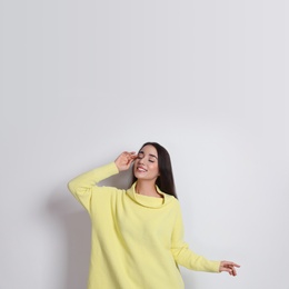 Photo of Beautiful young woman wearing yellow warm sweater on white background