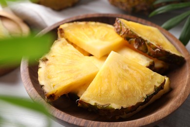 Photo of Pieces of tasty ripe pineapple in bowl on table, closeup