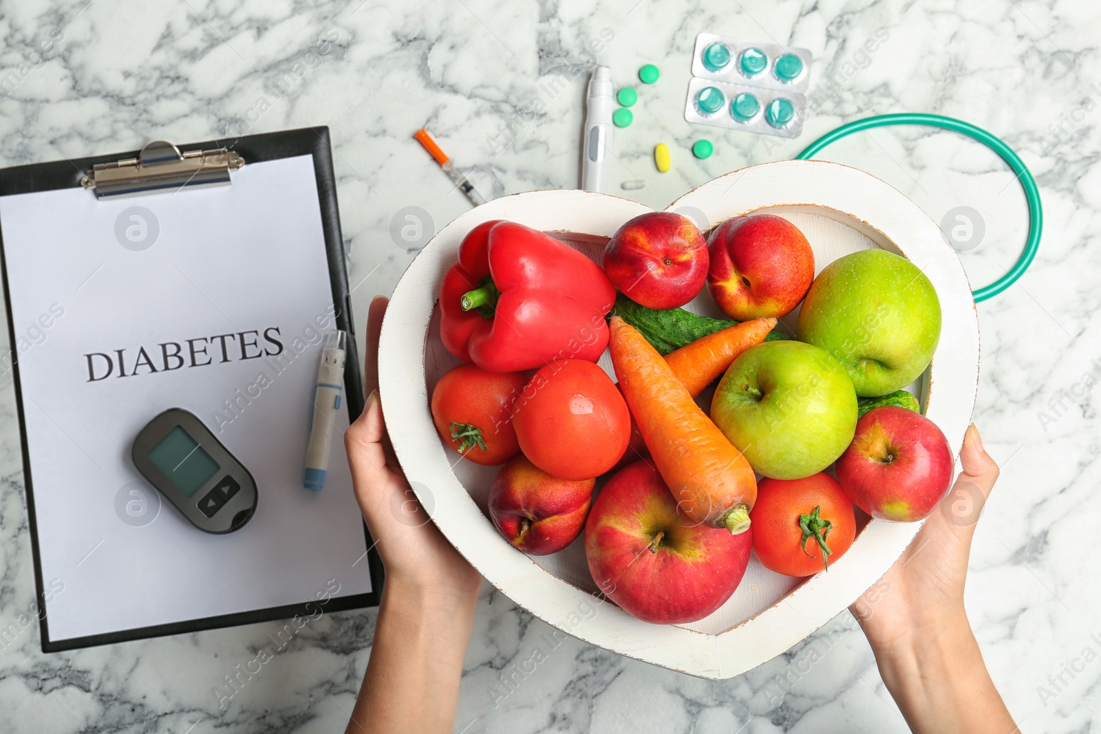 Photo of Woman holding tray with fruits and vegetables over table, top view. Diabetes diet