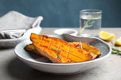 Photo of Plate with baked sweet potato slices on table