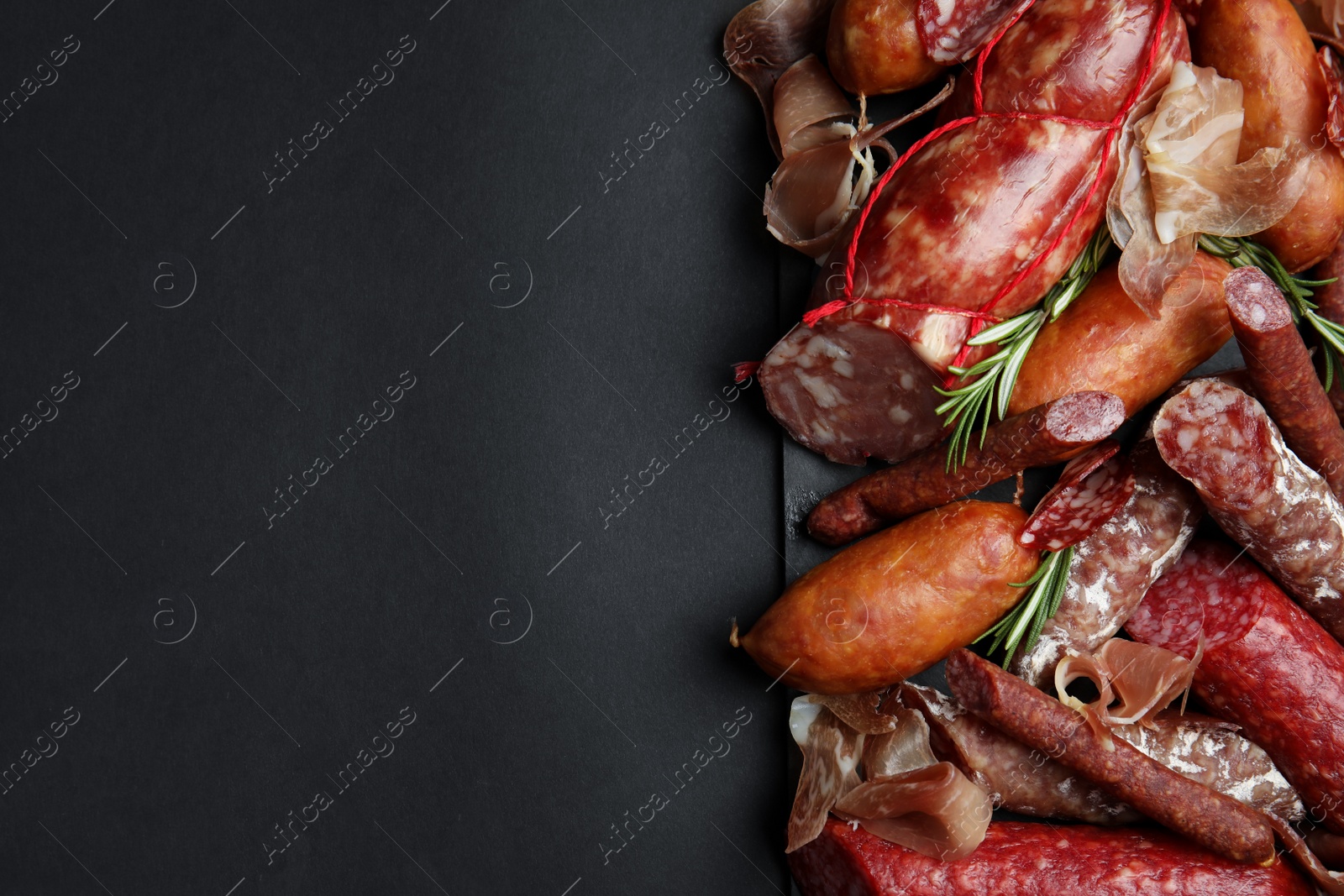 Photo of Different types of sausages served on black background, flat lay. Space for text