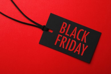 Image of Tag with phrase BLACK FRIDAY on red background, top view