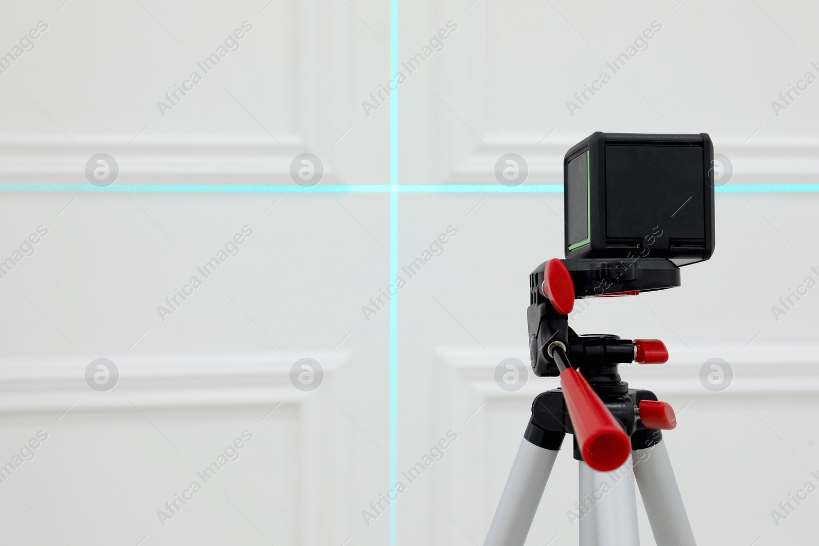 Photo of Cross line laser level on tripod in front of white wall