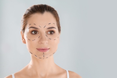 Portrait of woman with marks on face against grey background, space for text. Cosmetic surgery