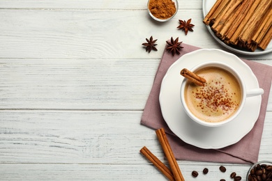 Delicious hot coffee with cinnamon on white wooden table, flat lay. Space for text