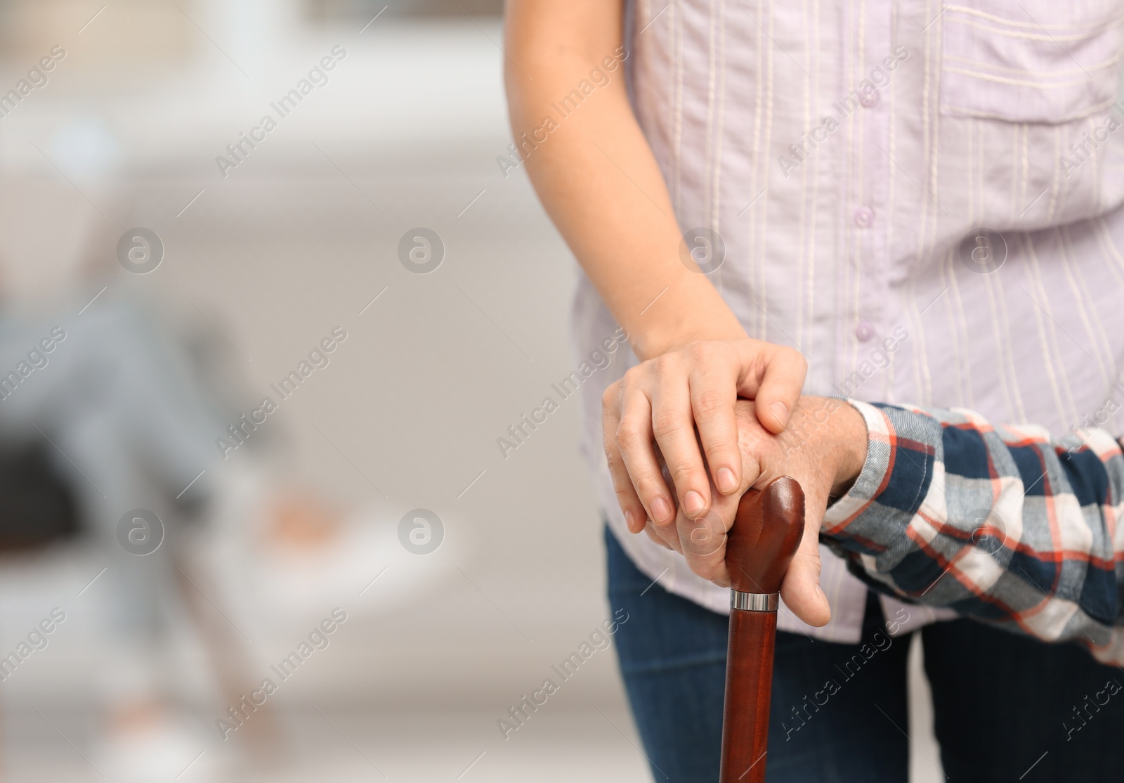 Photo of Female caregiver with elderly man, focus on hands. Space for text