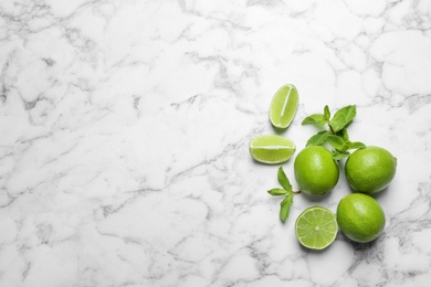 Photo of Fresh ripe limes on marble background, top view