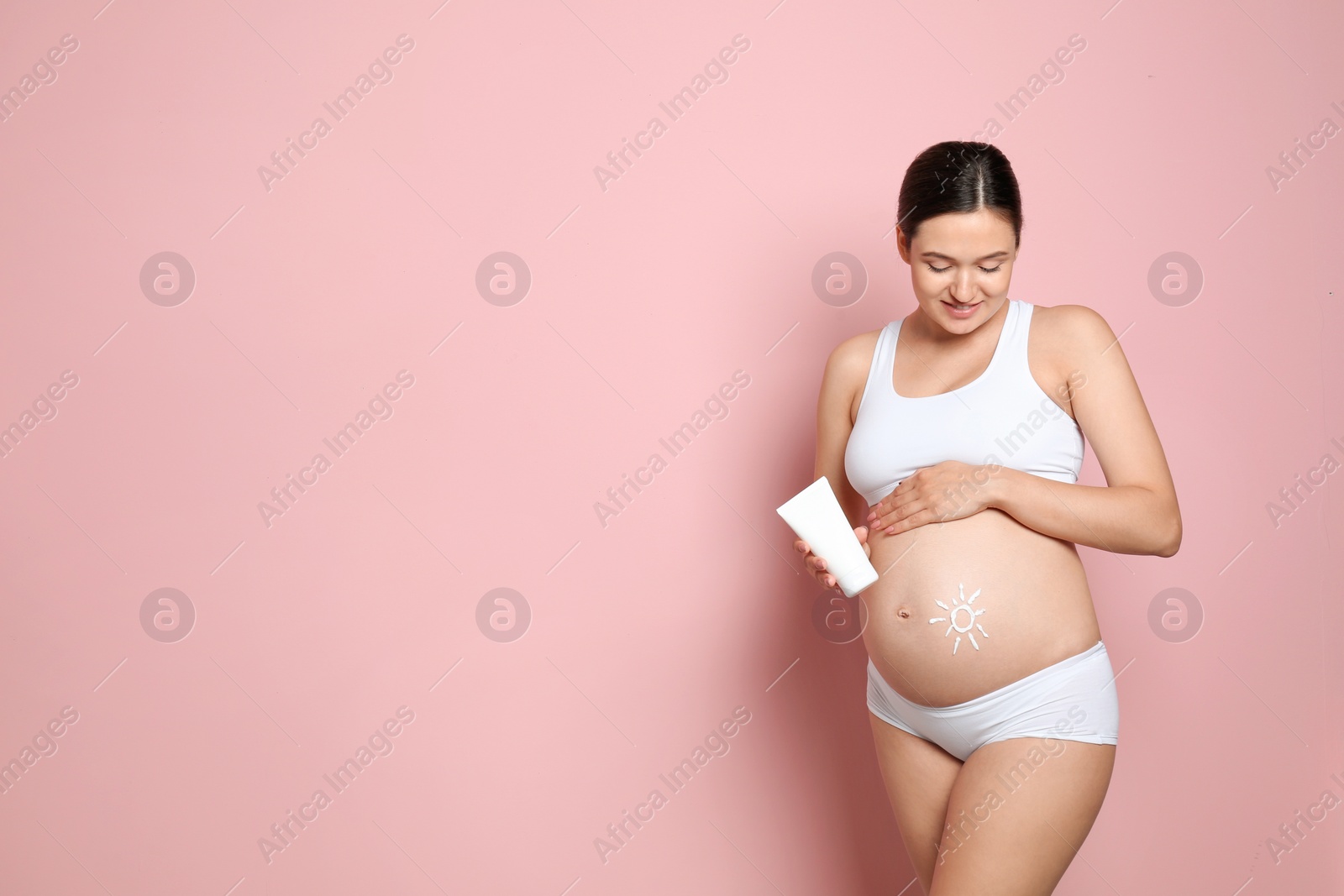 Photo of Sun painted with body cream on pregnant woman's belly against color background. Space for text