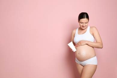 Sun painted with body cream on pregnant woman's belly against color background. Space for text