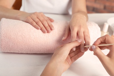 Photo of Manicurist filing client's nails at table, closeup. Spa treatment