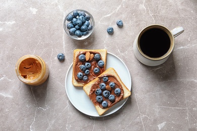 Flat lay composition with toast bread, blueberries, chocolate paste and cup of coffee on grey background