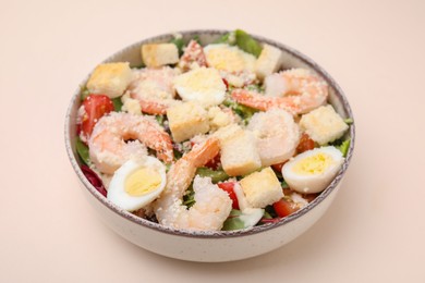 Photo of Delicious Caesar salad with shrimps on beige background, closeup