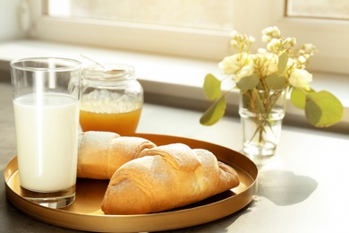 Photo of Tray with delicious croissants and glass of milk on table