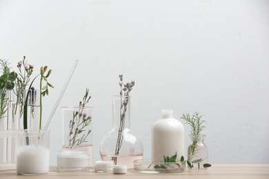 Photo of Herbal cosmetic products, laboratory glassware and ingredients on wooden table