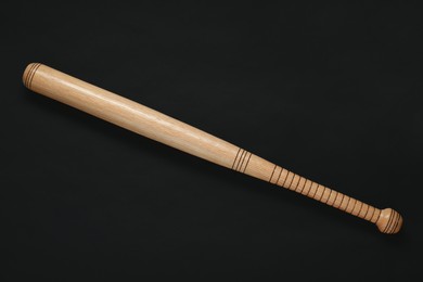 Photo of Wooden baseball bat on black background, top view. Sports equipment