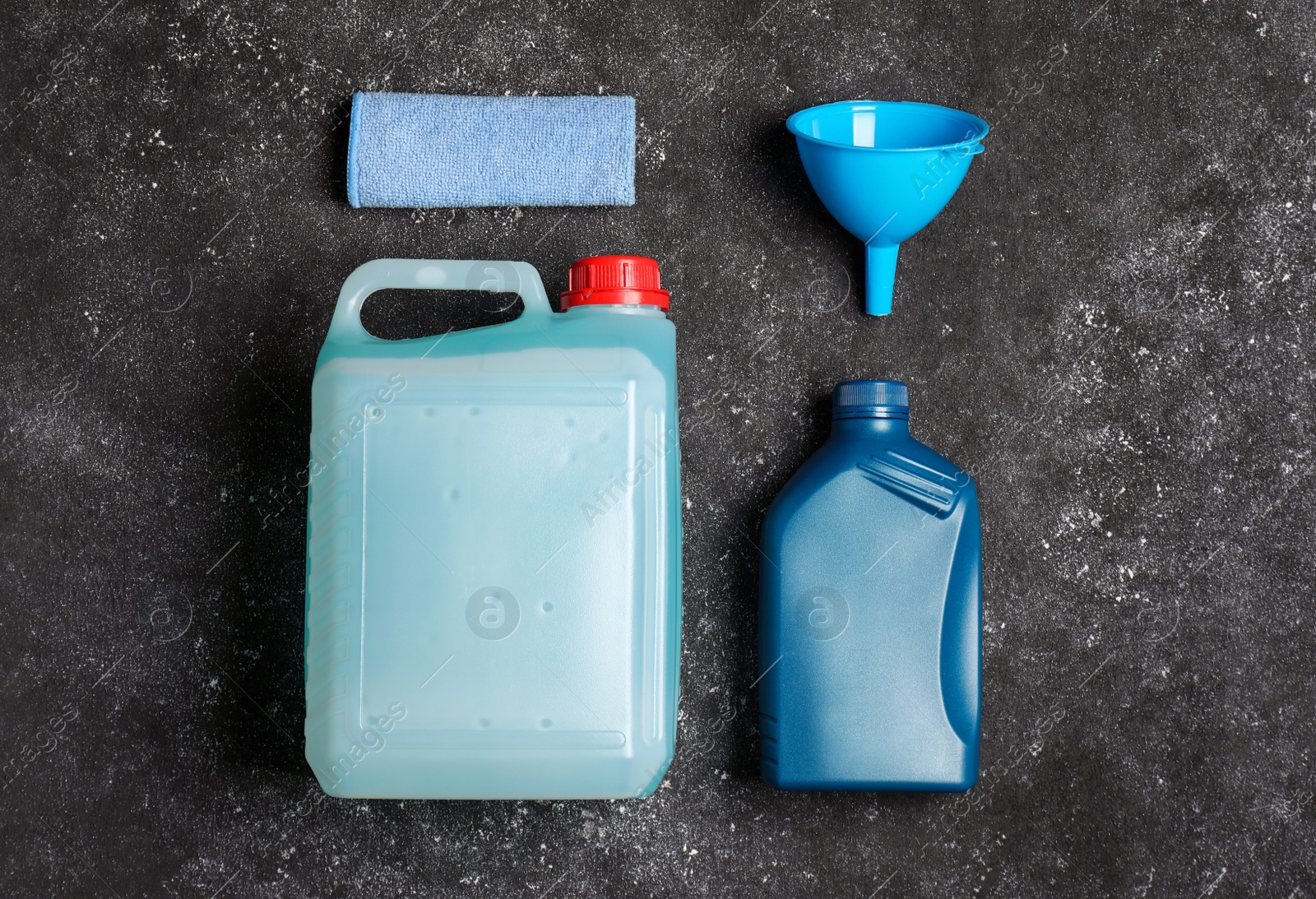 Photo of Canisters with motor oil and plastic funnel on grey table, top view