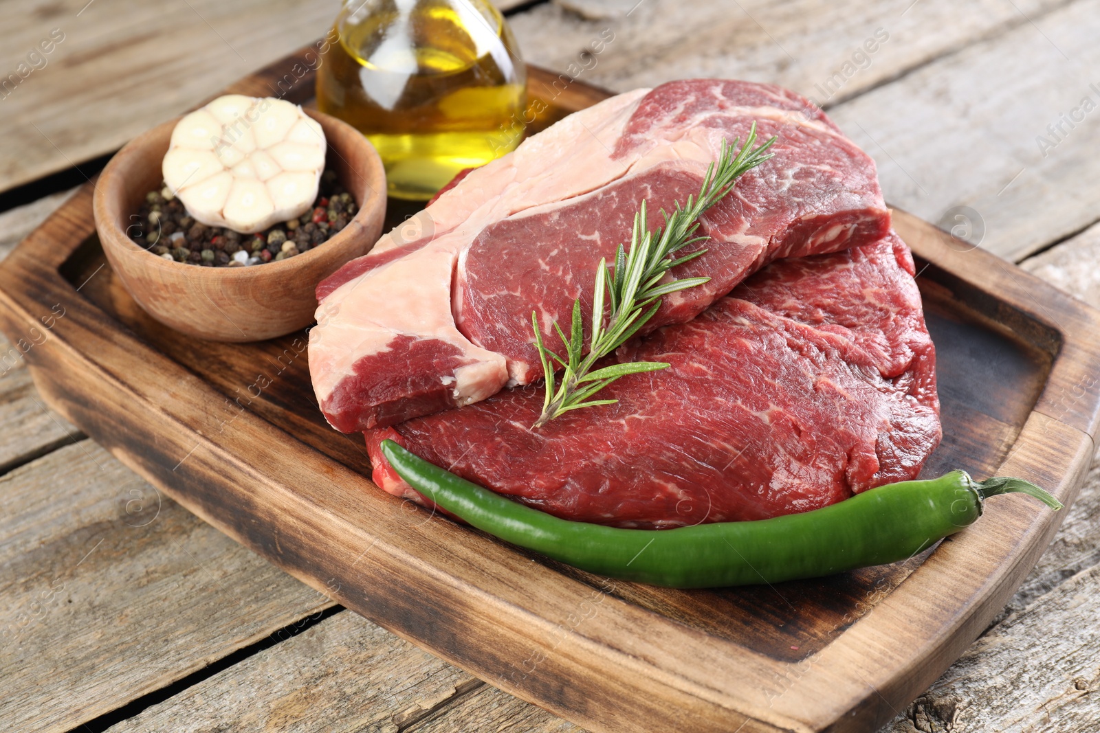 Photo of Fresh raw beef cut with spices on wooden table, closeup