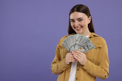 Happy woman with dollar banknotes on purple background, space for text