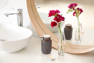 Photo of Beautiful spring freesia flowers on countertop in bathroom