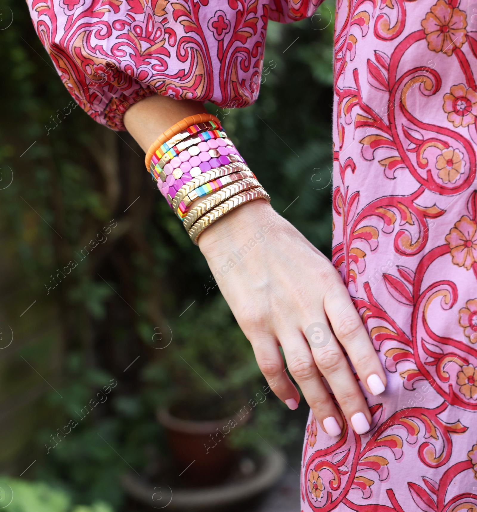 Photo of Woman wearing many stylish bracelets outdoors, closeup