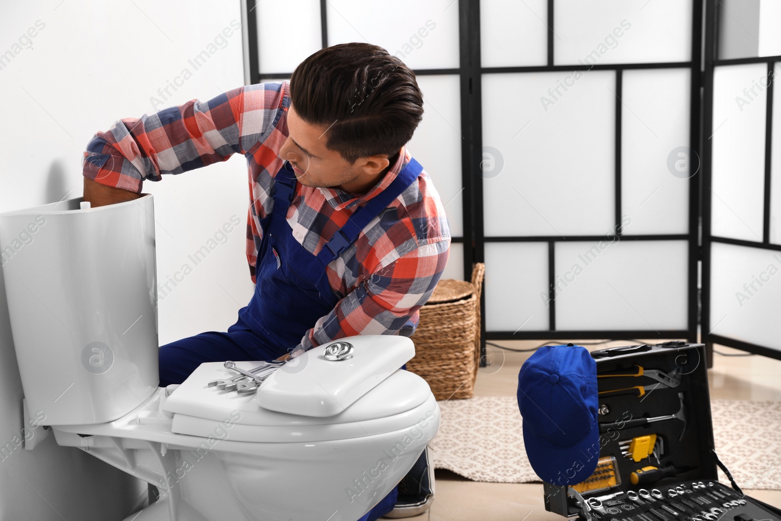 Photo of Professional plumber working with toilet bowl in bathroom