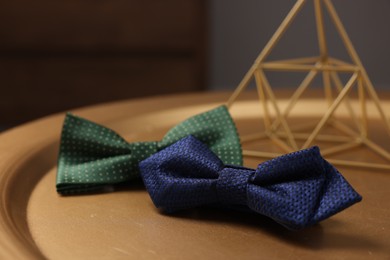 Photo of Stylish color bow ties on golden table, closeup