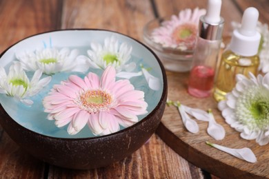 Photo of Spa composition. Bowl with water and beautiful flowers on wooden table, closeup. Space for text